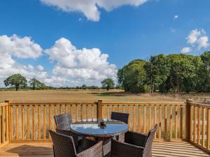 a patio with a table and chairs on a wooden deck at Cabin Hideaways, Glencraig - Uk38359 in Mattishall