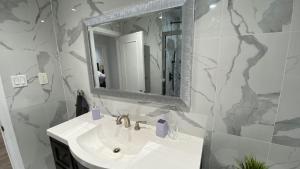 a white bathroom with a sink and a mirror at Spectacular 3 BR 2 WR House - Close to Airport in Toronto