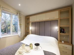 a bedroom with a bed with cups and saucers on a table at Winchester Lodge at Daisy Bank Caravan Park in Hyssington