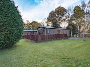 a small cabin in a yard with a fence at Winchester Lodge at Daisy Bank Caravan Park in Hyssington