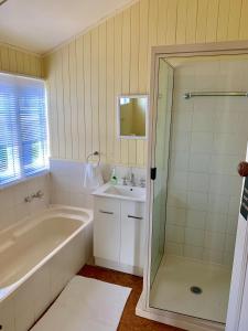 a bathroom with a tub and a sink and a shower at Rosellas on Corundum Cottage - treat yourself! in Stanthorpe