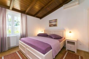 - une chambre avec un lit doté de draps violets et une fenêtre dans l'établissement Apartment Brela 2717c, à Brela