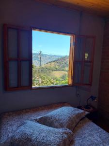 a bedroom with a window with a view of a mountain at Chalé Alto da Serra in Gonçalves +2 photos