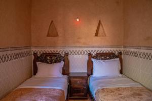 dos camas sentadas una al lado de la otra en una habitación en Maison etoile du desert en Aït Boukha