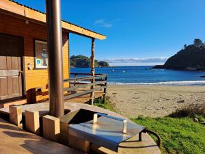 a house on the beach with a bench in front at Borde Mar, Hostal & Cabañas, Bahía Mansa in Bahía Mansa
