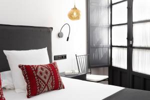 una camera con letto, cuscino rosso e sedia di Palacete Molina a Siviglia