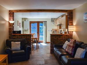 a living room with two leather couches and a kitchen at Poppy Cottage - Uk40102 in Dunvant