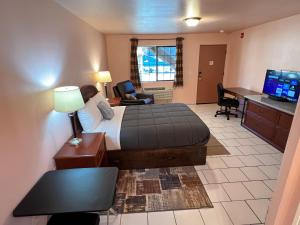 Habitación de hotel con cama, escritorio y TV. en Frazier View Motel, en Frazier Park