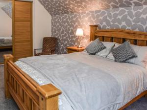 a bedroom with a wooden bed and a chair at Gleaner Lea in Campbeltown