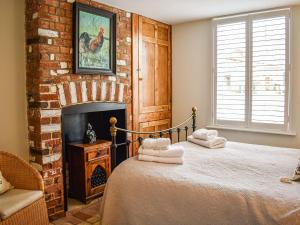 a bedroom with a bed and a brick fireplace at May Cottage in Rendham