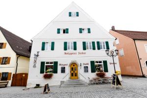 een wit gebouw met groene luiken en een gele deur bij Pension Ferber in Monheim