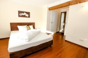 a bedroom with a bed with white sheets and a wooden floor at Pension Ferber in Monheim +5 photos
