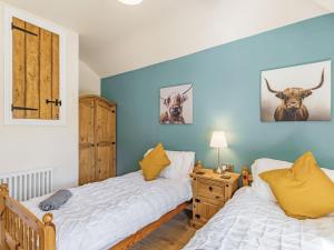 two beds in a bedroom with blue walls at Spa Cottage in Bakewell