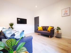 a living room with a blue couch and yellow pillows at Spacious Townhouse 5 Mins to Liverpool City Centre With Free Parking in Liverpool