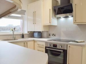 a kitchen with white cabinets and a stove top oven at Princess Court Apartment in Llanelli