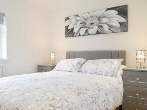 a bedroom with a bed with a flower picture on the wall at Princess Court Apartment in Llanelli