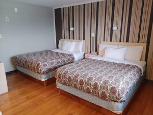 two beds in a hotel room with wooden floors at Magnuson Hotel Creston in Creston