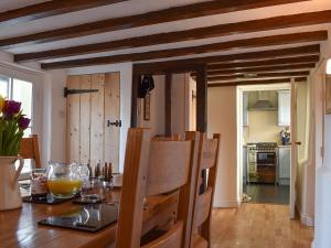 comedor con mesa de madera y cocina en Brushmaker Cottage, en Diss