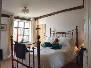 un osito de peluche sentado en una cama en un dormitorio en Brushmaker Cottage, en Diss