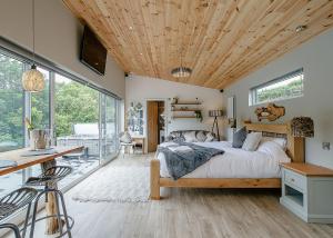 Nant-y-coed Lodges في Mochdre: غرفة نوم بسرير كبير بسقف خشبي