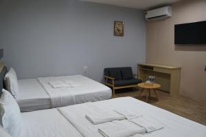 a hotel room with two beds and a chair at Unikarya Lodge in Kota Kinabalu