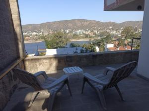 2 Stühle und ein Tisch auf einem Balkon mit Aussicht in der Unterkunft InterLaken Apart & Suites in Villa Carlos Paz