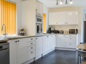 a white kitchen with white cabinets and appliances at The Garden House in Folkestone