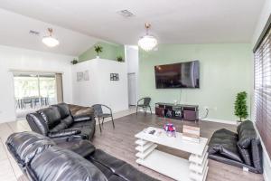 sala de estar con muebles de cuero y TV de pantalla plana en Gorgeous Fully Furnished 2-Bedroom Luxury Villa, en Kissimmee