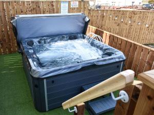 a hot tub sitting on the grass next to a fence at Old Stables Cottage in Hunwick