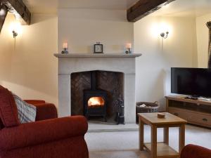 a living room with a fireplace and a tv at Far Barsey Cottage in Sowerby Bridge