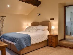 a bedroom with a bed with a blue blanket on it at Far Barsey Cottage in Sowerby Bridge