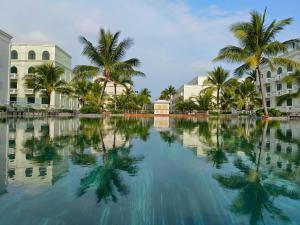 una piscina de agua con palmeras y edificios en Larosa Hotel en Phu Quoc