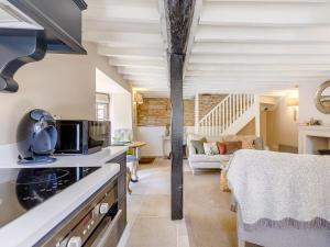 a kitchen with a stove top oven next to a living room at Hope Cottage in Longborough