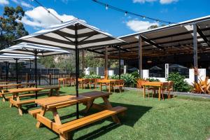 - un groupe de tables de pique-nique et de chaises sous un parasol dans l'établissement Salisbury Hotel Motel, à Brisbane