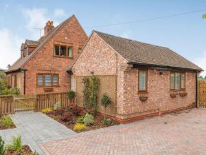 a brick house with a fence in front of it at The Old Farmhouse in Longford