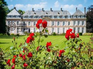 a large building with red flowers in front of it at Château de Sissi in Sassetot-le-Mauconduit