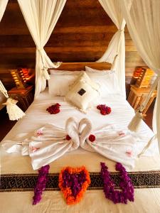 ein Bett mit weißer Bettwäsche und Blumen darauf in der Unterkunft Griyatama Bungalow in Nusa Penida