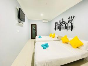 two beds in a room with a tv on the wall at FAT MERMAID GUESTHOUSE in Pantai Cenang