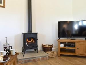 a living room with a stove and a tv at Shepherds Den in Crakehall