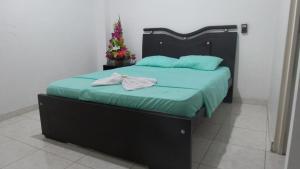 a bed with a black headboard and green sheets and a christmas tree at Hotel Boutique San Juan in Neiva