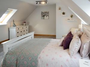 Un dormitorio con una cama con almohadas. en Rose Cottage en Dingwall