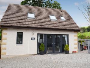 una pequeña casa con un perro sentado frente a ella en Rose Cottage en Dingwall