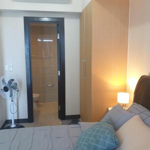 a bedroom with a bed and a bathroom with a fan at Uptown Parksuites Tower 1 BGC in Manila