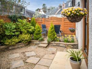 a garden with chairs and plants and a fence at By The Sea in Avoch