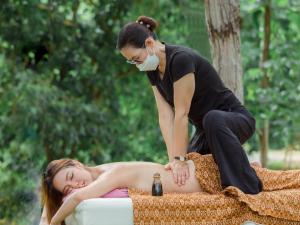 a woman laying on a bed with a woman wearing a mask at Hin Khong Villa - a tropical surprise in Ban Huai Sai