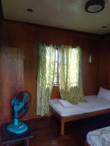 um pequeno quarto com uma cama e uma janela em Nellie's Tourist Inn- Port Barton em San Vicente