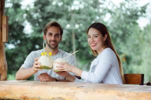 um homem e uma mulher sentados à mesa com bebidas em Hin Khong Villa - a tropical surprise em Ban Huai Sai