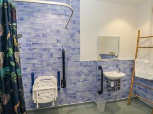 een blauw betegelde badkamer met een wastafel en een spiegel bij 12 Malthall in Swansea