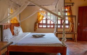a bedroom with a canopy bed and a window at Christina House in Arusha +4 photos