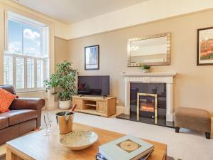 a living room with a fireplace and a tv at Bank House Apartment in Newnham